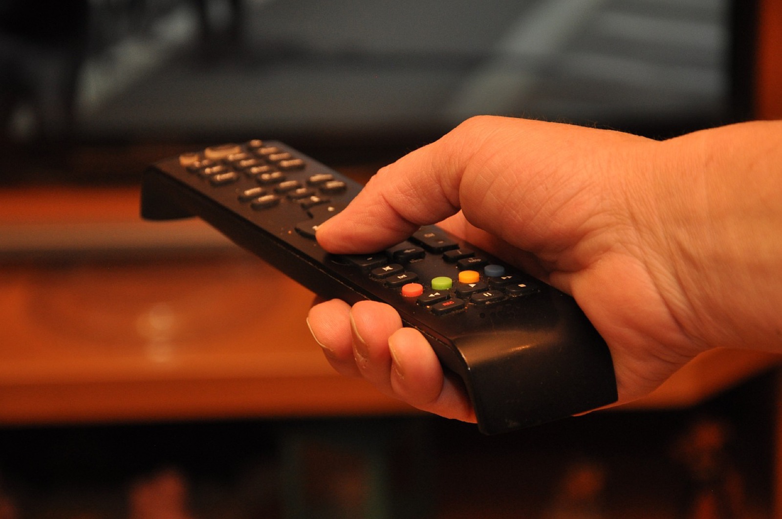 Viewer relaxing on a sofa with a remote, watching Norwegian IPTV channels on a smart TV