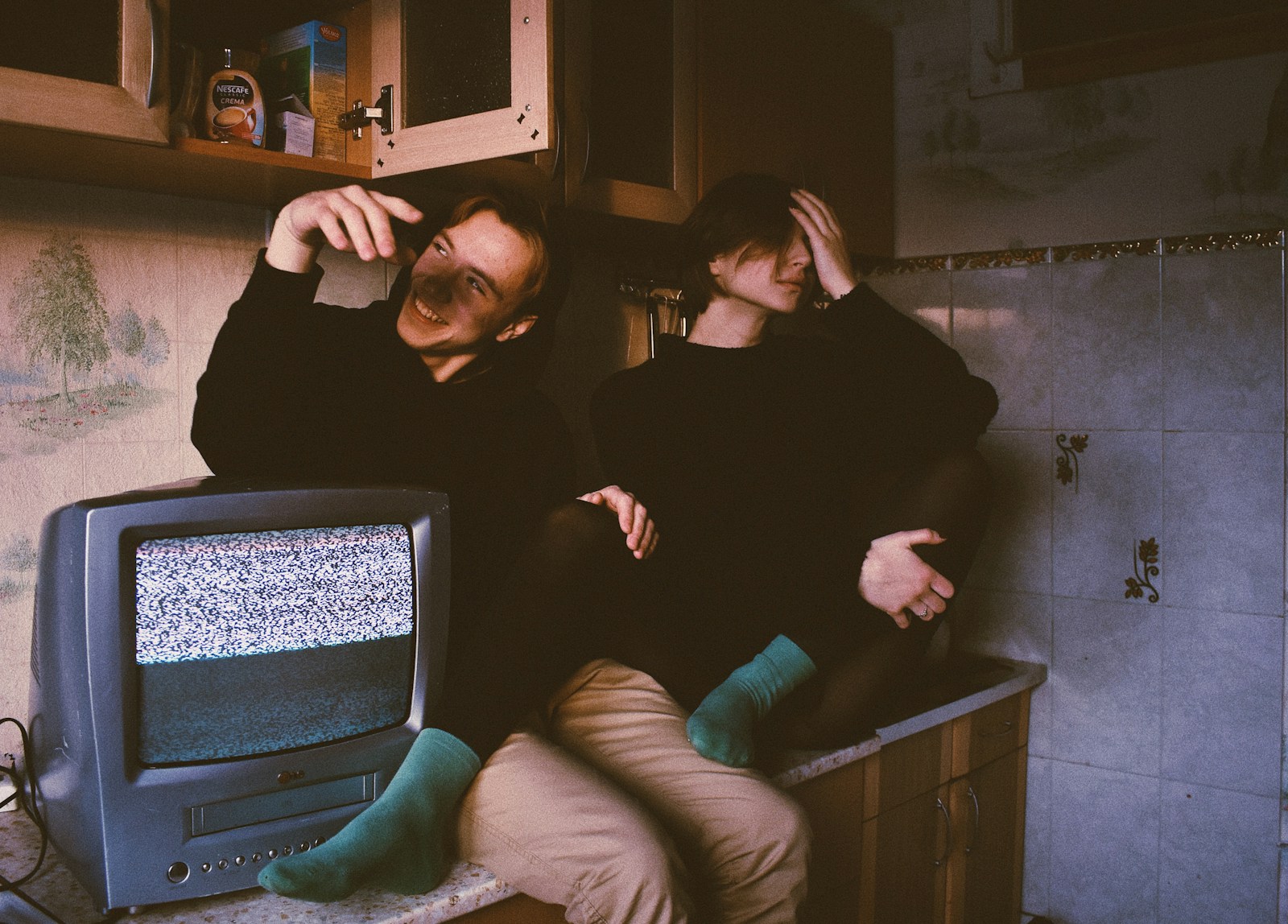 Two men sitting beside an old CRT television — cable TV's past